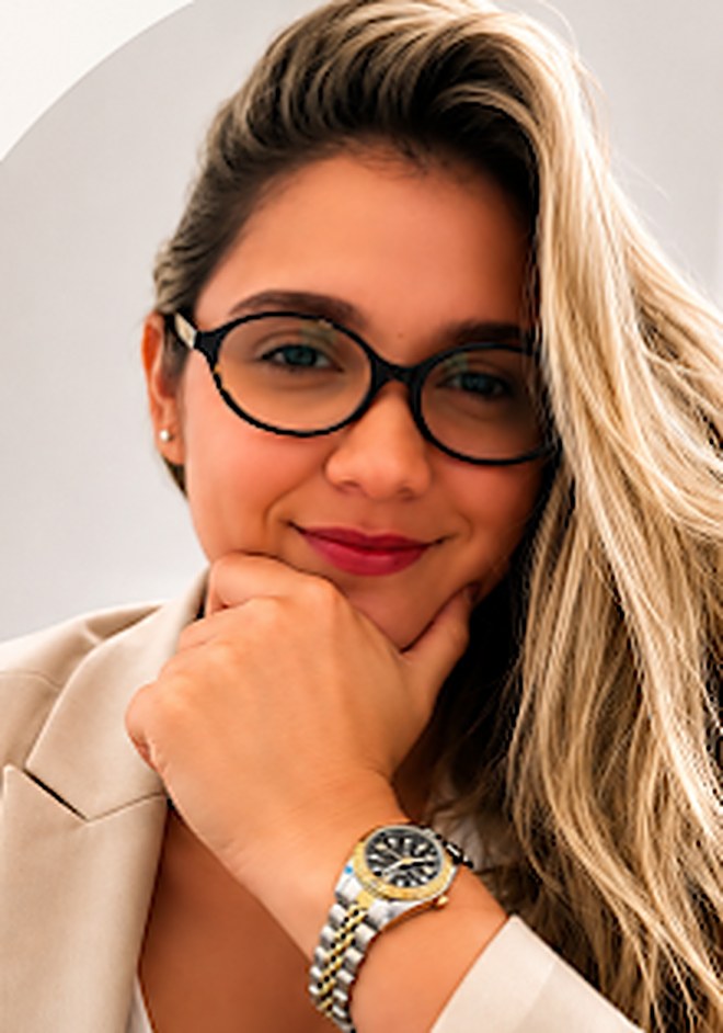 Retrato da psicóloga Larissa Gomes, sorrindo, de óculos e blazer claro